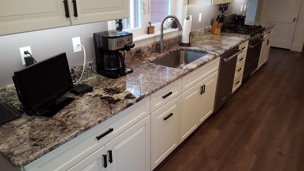 Design ideas for a large traditional l-shaped eat-in kitchen in Boston with an undermount sink, raised-panel cabinets, white cabinets, granite benchtops, stainless steel appliances, vinyl floors and with island.