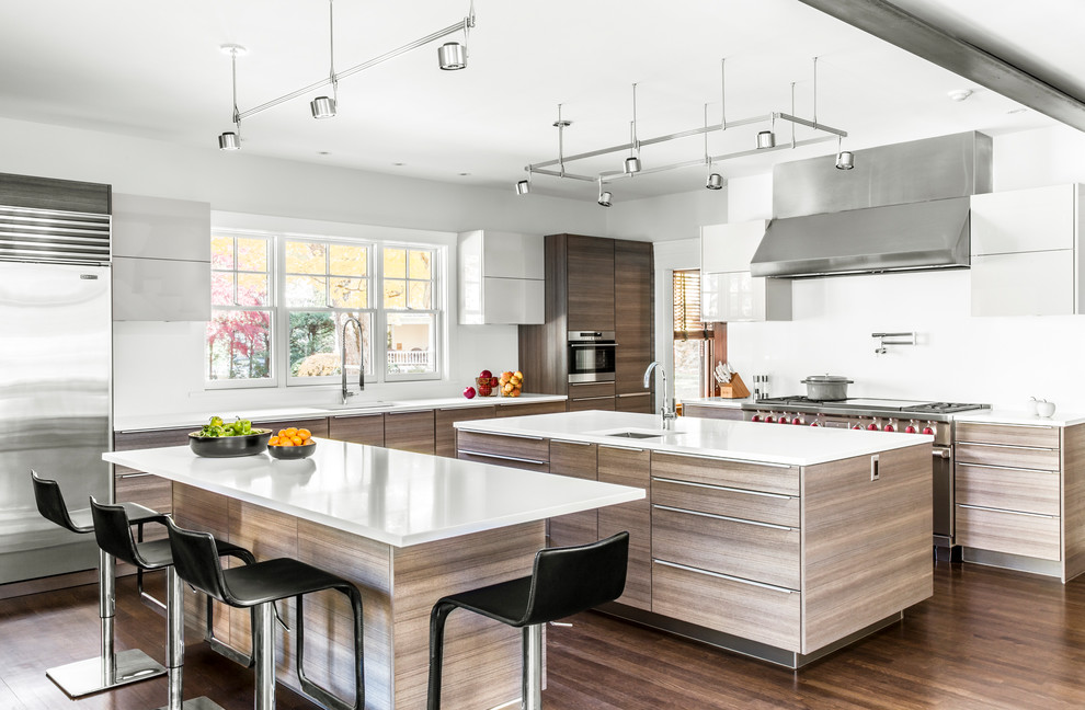 Kitchen - large contemporary brown floor and dark wood floor kitchen idea in Boston with an undermount sink, flat-panel cabinets, white backsplash, stainless steel appliances, two islands and light wood cabinets