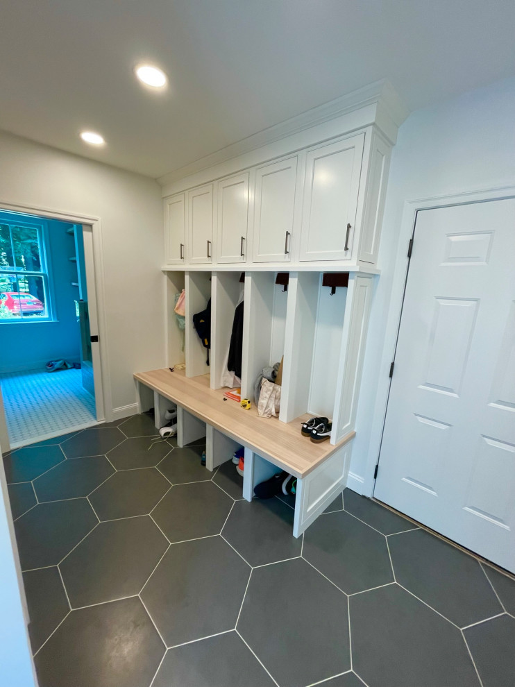 This is an example of a medium sized modern boot room in Boston with white walls, ceramic flooring, a single front door, a white front door and grey floors.