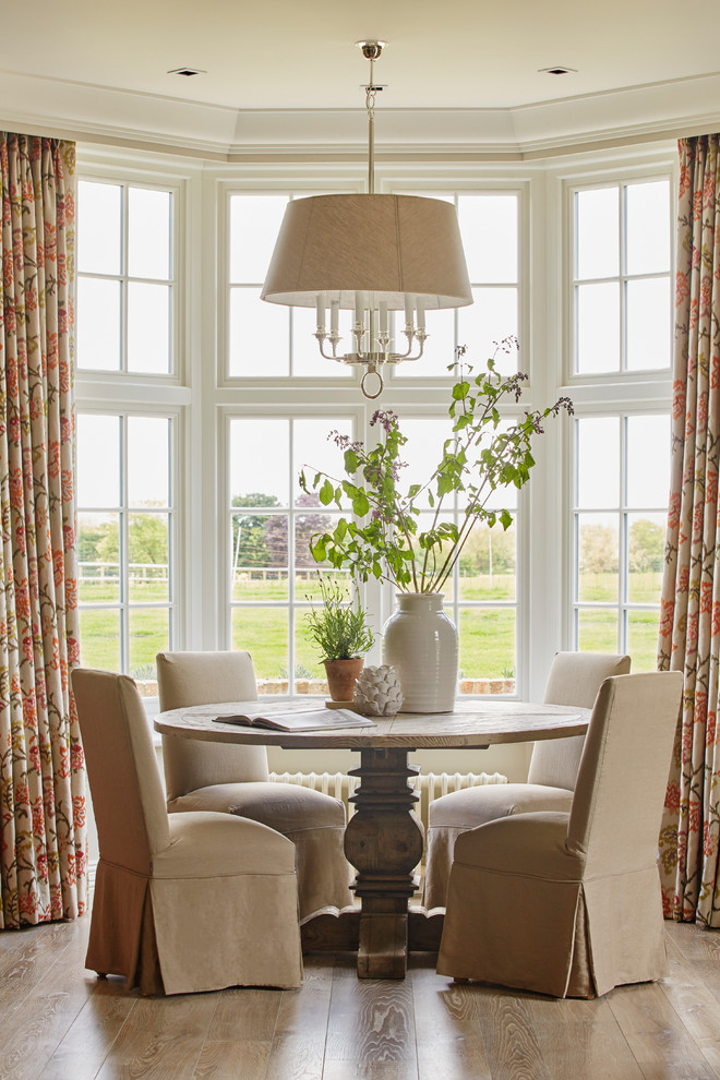 This is an example of a country dining room with light hardwood floors and brown floor.