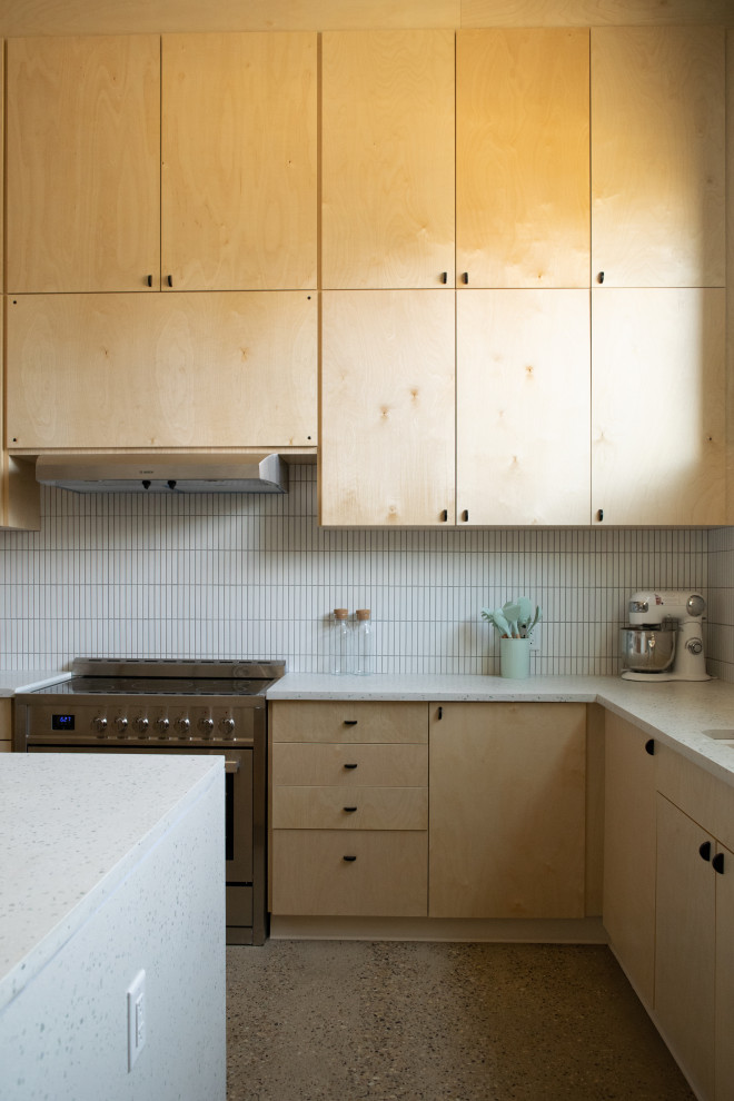 Large scandinavian u-shaped separate kitchen in Stockholm with an undermount sink, flat-panel cabinets, light wood cabinets, terrazzo benchtops, white splashback, ceramic splashback, stainless steel appliances, concrete floors, with island, brown floor, green benchtop and vaulted.