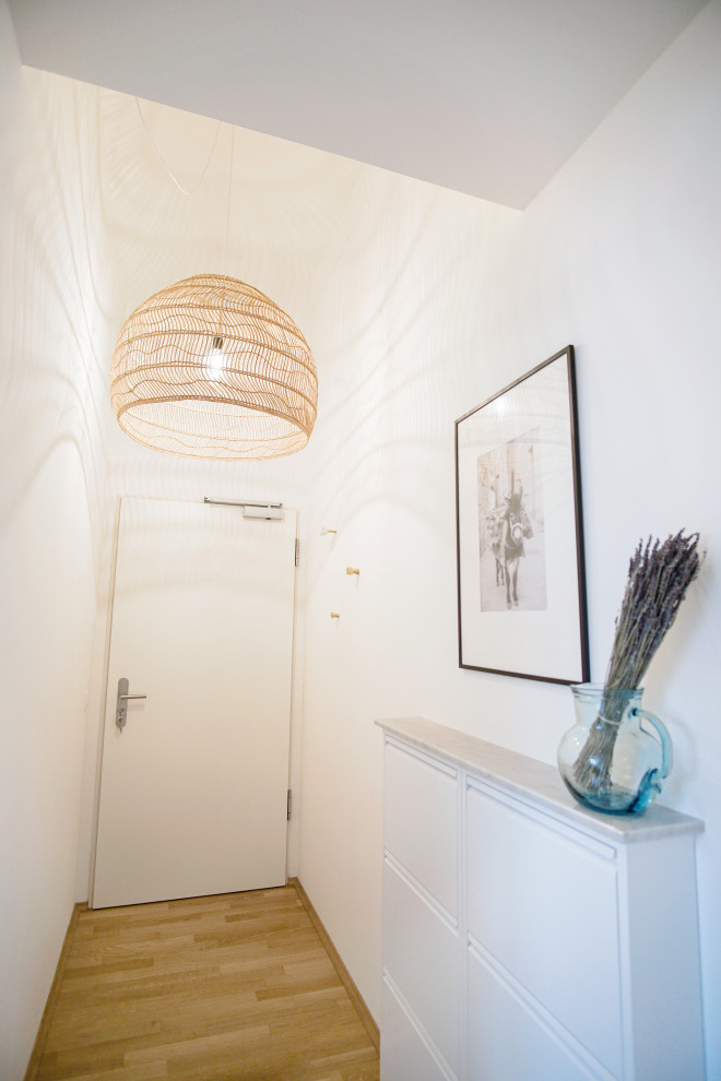 This is an example of a mediterranean hallway in Munich with white walls, medium hardwood floors and brown floor.