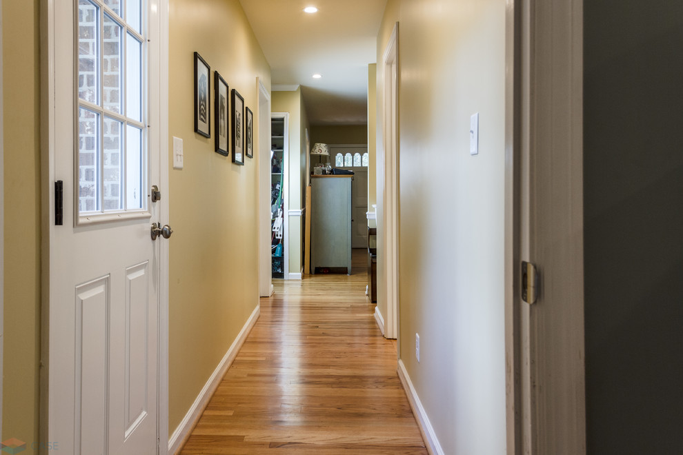 This is an example of a mid-sized traditional hallway in Charleston with yellow walls, light hardwood floors and orange floor.