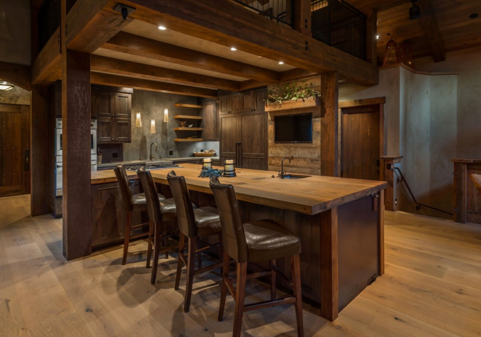 Inspiration for a rustic l-shaped open concept kitchen remodel with a farmhouse sink, recessed-panel cabinets, dark wood cabinets, stainless steel appliances and an island
