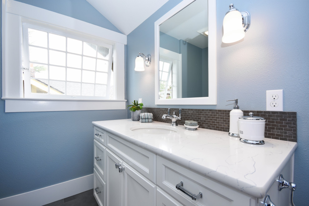 This is an example of a small traditional 3/4 bathroom in Seattle with open cabinets, white cabinets, a drop-in tub, an alcove shower, a one-piece toilet, multi-coloured tile, marble, blue walls, porcelain floors, an integrated sink, quartzite benchtops, grey floor, a shower curtain and white benchtops.