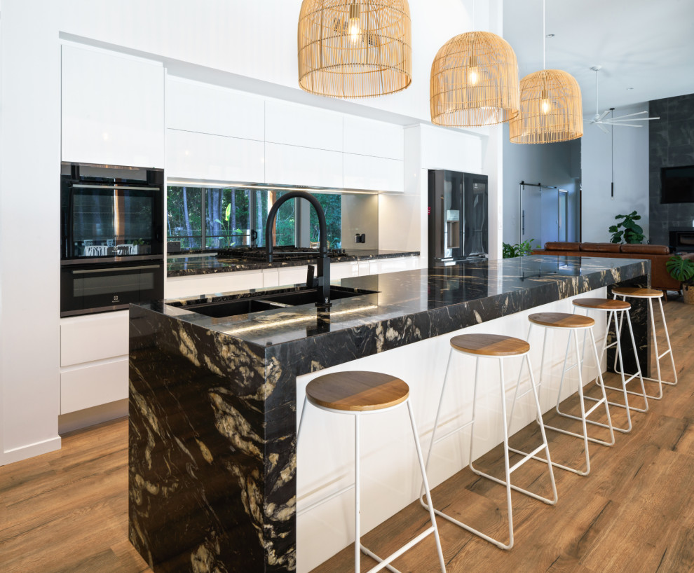 Design ideas for a contemporary galley kitchen in Sunshine Coast with an undermount sink, flat-panel cabinets, white cabinets, window splashback, black appliances, dark hardwood floors, with island, brown floor and black benchtop.
