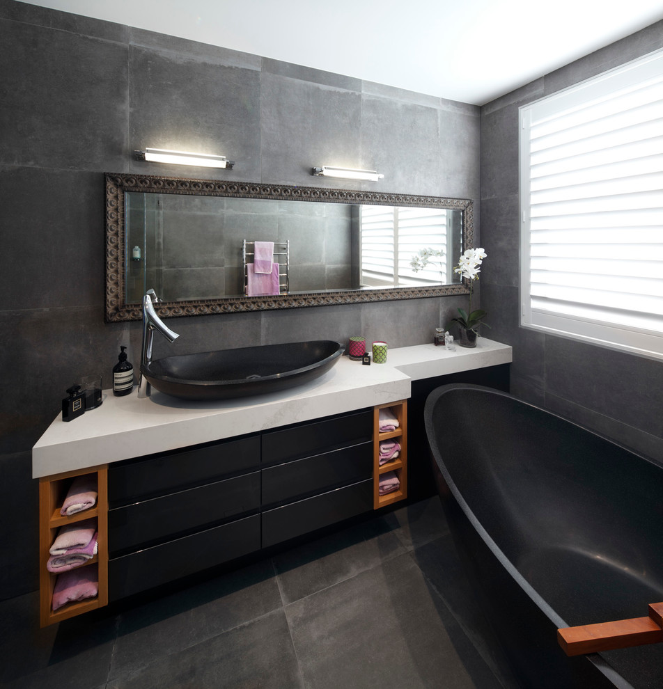 This is an example of a mid-sized contemporary master bathroom in Sydney with recessed-panel cabinets, medium wood cabinets, a freestanding tub, a corner shower, a one-piece toilet, gray tile, stone tile, grey walls, ceramic floors, a vessel sink and soapstone benchtops.