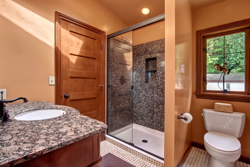 Photo of a mid-sized traditional 3/4 bathroom in Seattle with an undermount sink, furniture-like cabinets, medium wood cabinets, granite benchtops, a one-piece toilet, beige tile, stone tile, orange walls and marble floors.