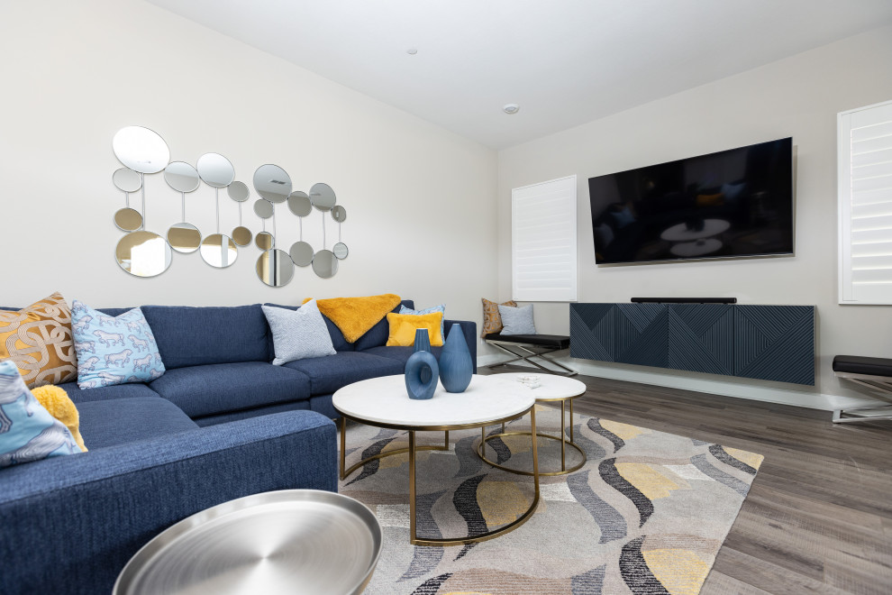 На фото: большая открытая гостиная комната в стиле ретро с серыми стенами, полом из винила, телевизором на стене и коричневым полом с