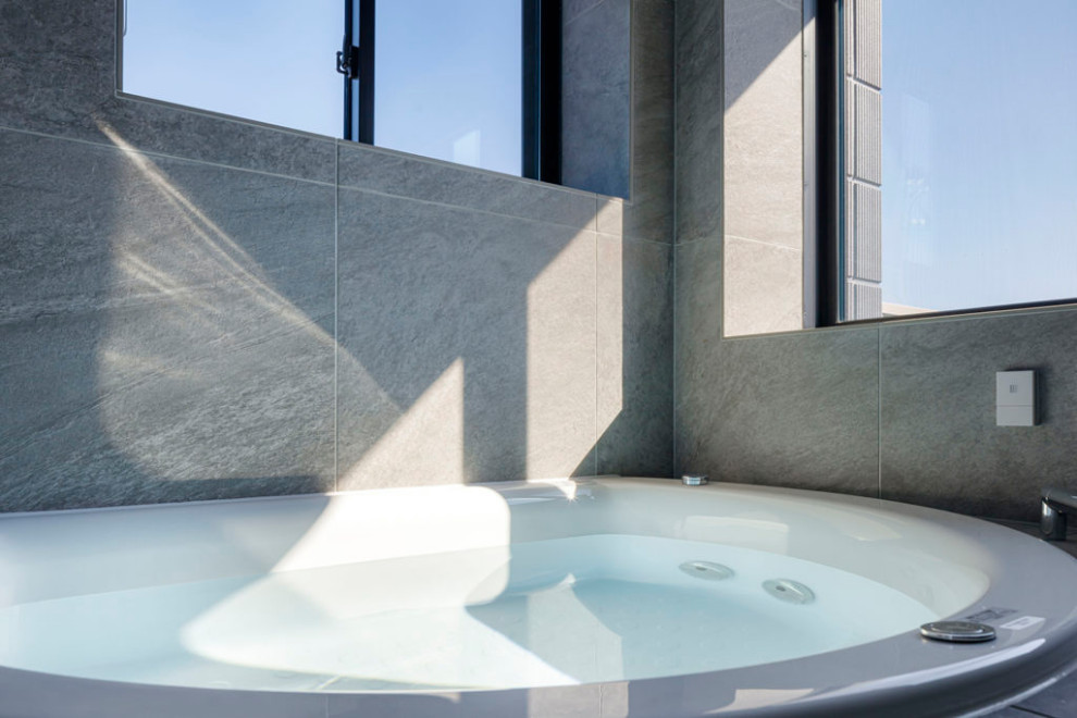 Esempio di una stanza da bagno moderna con piastrelle grigie, piastrelle in pietra, pareti grigie, pavimento in gres porcellanato, pavimento grigio, nicchia e soffitto ribassato