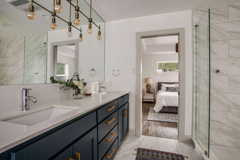 This is an example of a mid-sized transitional master wet room bathroom in Dallas with shaker cabinets, blue cabinets, a freestanding tub, a two-piece toilet, gray tile, porcelain tile, white walls, porcelain floors, an undermount sink, engineered quartz benchtops, grey floor, a hinged shower door and white benchtops.