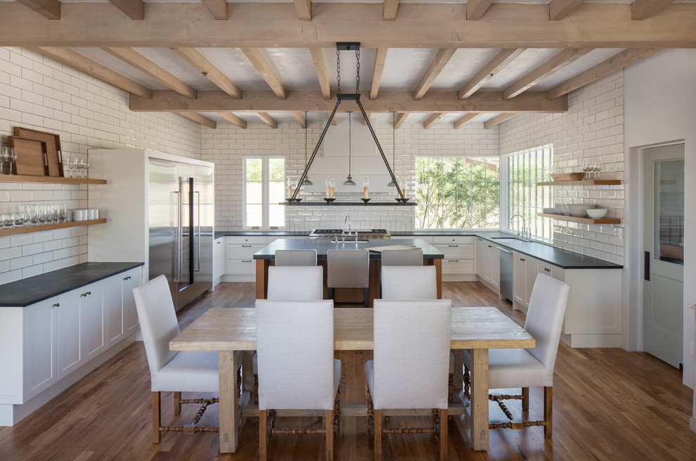 Large transitional u-shaped medium tone wood floor and brown floor open concept kitchen photo in Phoenix with shaker cabinets, white cabinets, soapstone countertops, white backsplash, ceramic backsplash, stainless steel appliances and an island