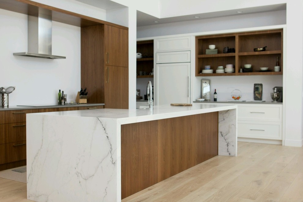 Design ideas for a large modern l-shaped kitchen pantry in Phoenix with a farmhouse sink, flat-panel cabinets, medium wood cabinets, granite benchtops, white splashback, stainless steel appliances, light hardwood floors, with island, beige floor and white benchtop.