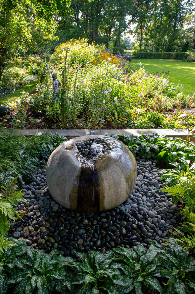 Diseño de jardín tradicional en patio trasero con fuente, exposición reducida al sol y piedra decorativa