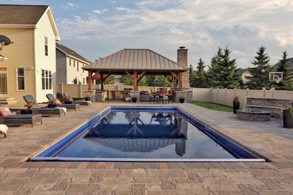This is an example of a mid-sized transitional backyard rectangular pool in Other with natural stone pavers.