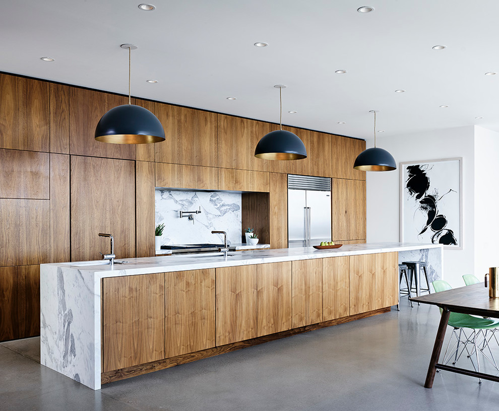 Design ideas for a modern open plan kitchen in Austin with an undermount sink, flat-panel cabinets, medium wood cabinets, marble benchtops, white splashback, stone slab splashback, stainless steel appliances, concrete floors, with island and grey floor.