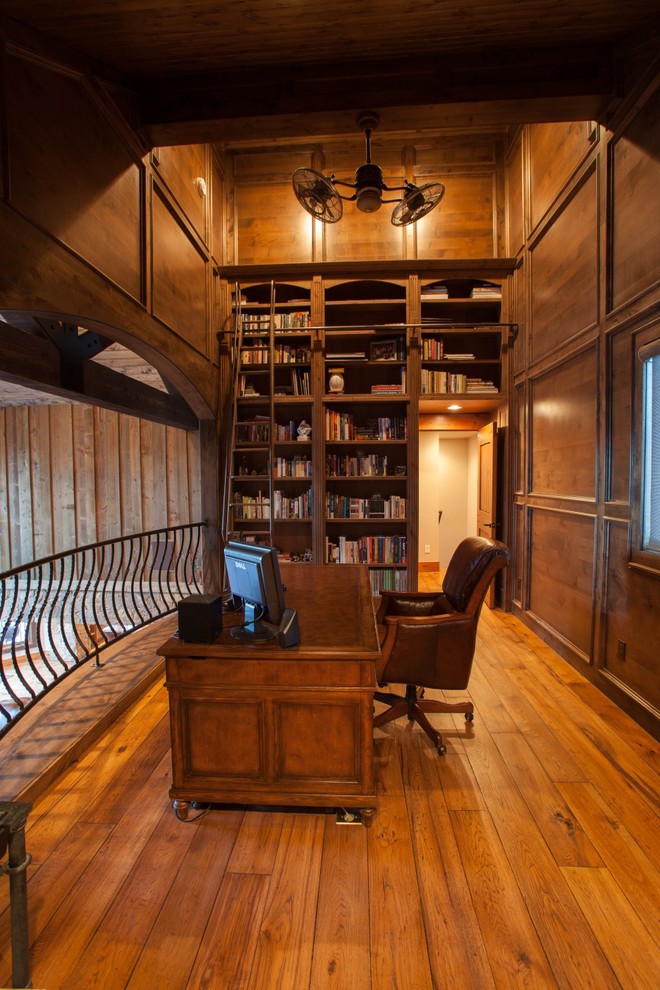 Inspiration for a mid-sized country home office in Denver with a library, brown walls, medium hardwood floors and a freestanding desk.