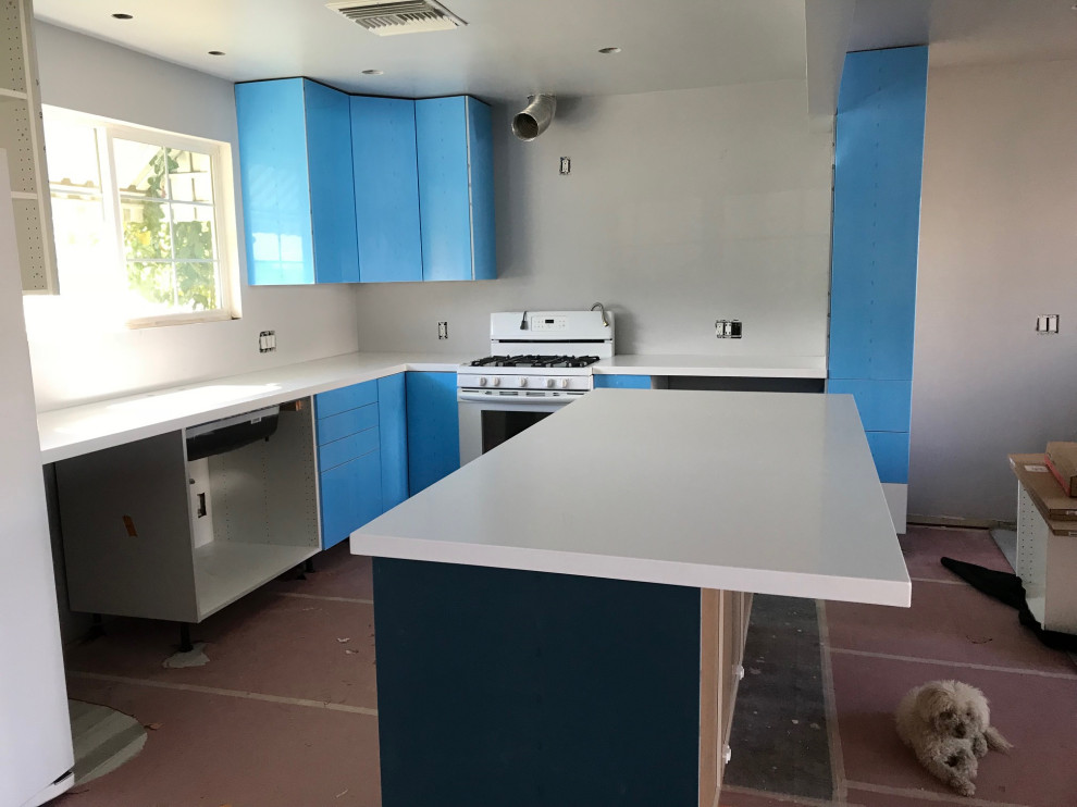 This is an example of a mid-sized modern l-shaped eat-in kitchen in Portland with an undermount sink, flat-panel cabinets, white cabinets, quartz benchtops, grey splashback, porcelain splashback, white appliances, porcelain floors, with island, multi-coloured floor and white benchtop.