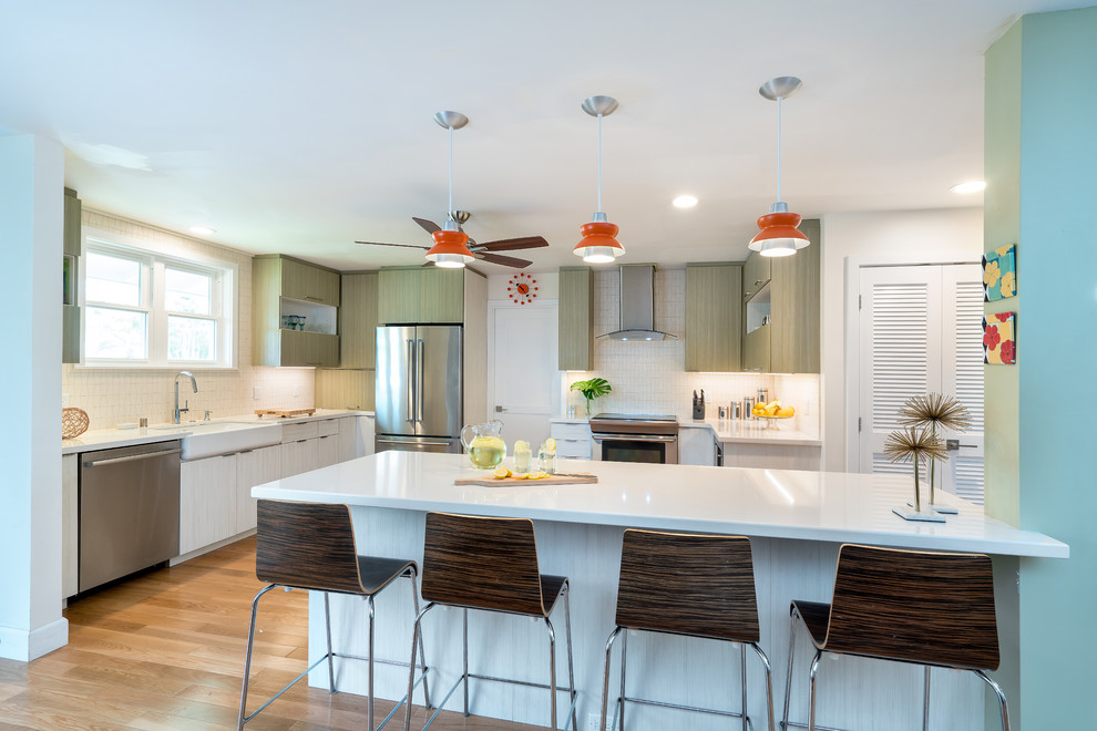 Photo of a large contemporary l-shaped eat-in kitchen in Hawaii with a farmhouse sink, flat-panel cabinets, white cabinets, quartz benchtops, white splashback, stainless steel appliances, with island, ceramic splashback and light hardwood floors.