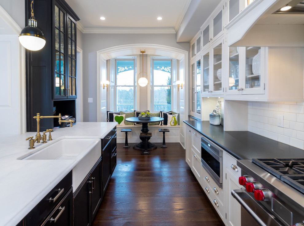 Design ideas for a transitional galley kitchen in Other with a farmhouse sink, shaker cabinets, white cabinets, white splashback, porcelain splashback, stainless steel appliances, dark hardwood floors, a peninsula, brown floor, black benchtop and soapstone benchtops.