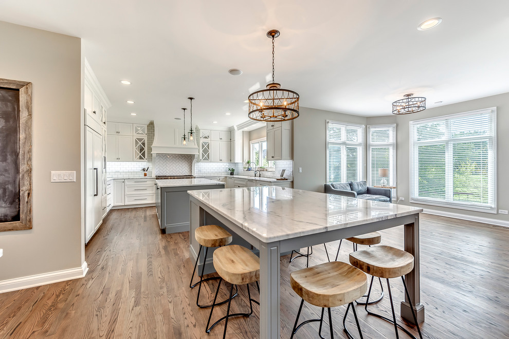 Example of a transitional open concept kitchen design in Chicago with white backsplash, subway tile backsplash and two islands
