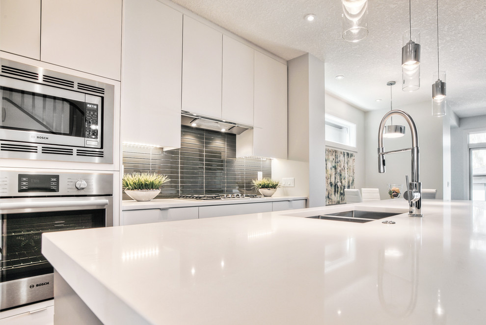 Photo of a modern kitchen in Calgary with flat-panel cabinets, stainless steel appliances and with island.