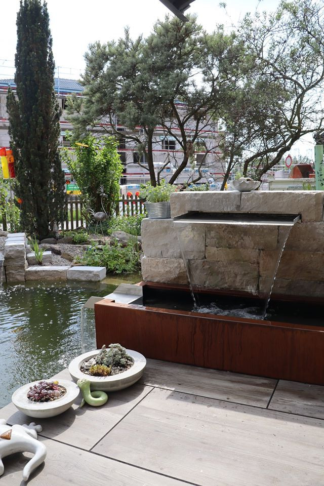 Photo of a contemporary backyard garden for spring in Nuremberg with with waterfall and natural stone pavers.