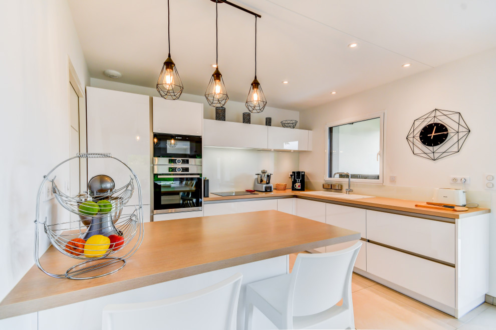 Inspiration for a mid-sized scandinavian l-shaped eat-in kitchen in Toulouse with a single-bowl sink, laminate benchtops, white splashback, glass sheet splashback, stainless steel appliances, ceramic floors, with island and beige floor.