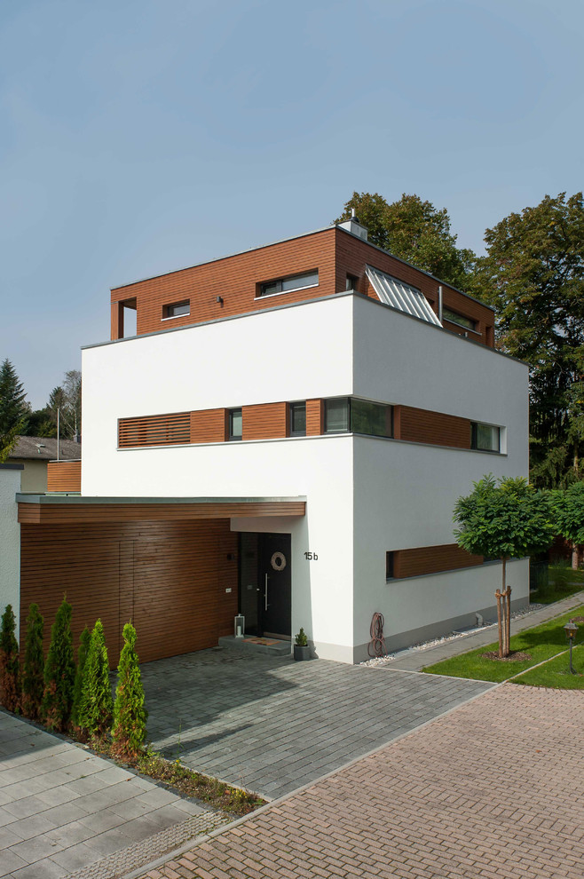 Design ideas for a mid-sized modern three-storey white exterior in Munich with a flat roof.