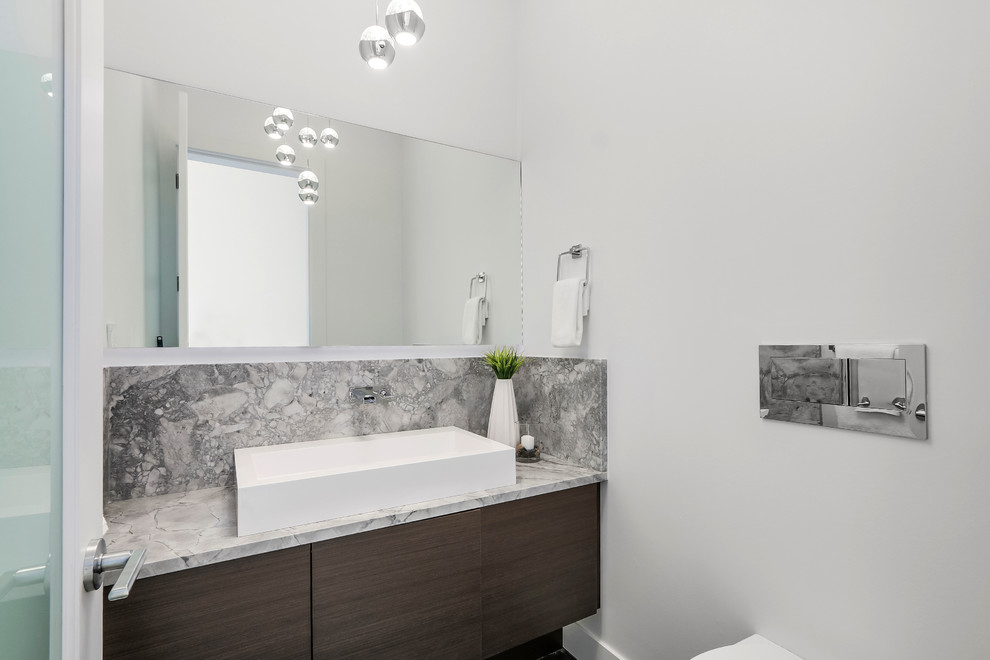 Small contemporary powder room in Vancouver with flat-panel cabinets, brown cabinets, a wall-mount toilet, white walls, porcelain floors, a pedestal sink, granite benchtops, black floor and grey benchtops.