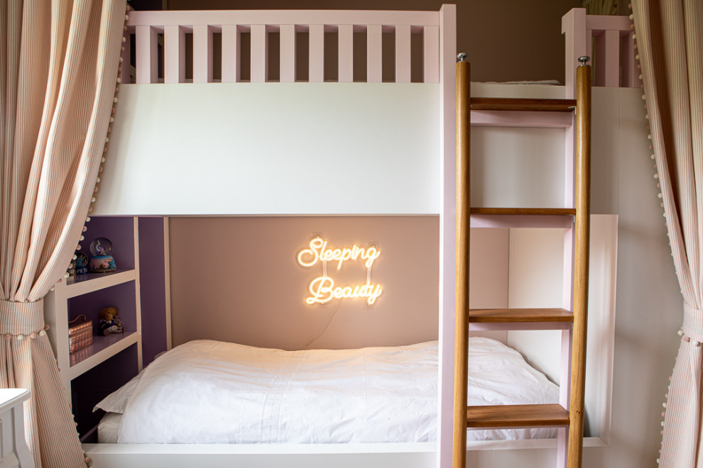 Photo of a mid-sized contemporary kids' bedroom for kids 4-10 years old and girls in London with pink walls, light hardwood floors, grey floor and wallpaper.