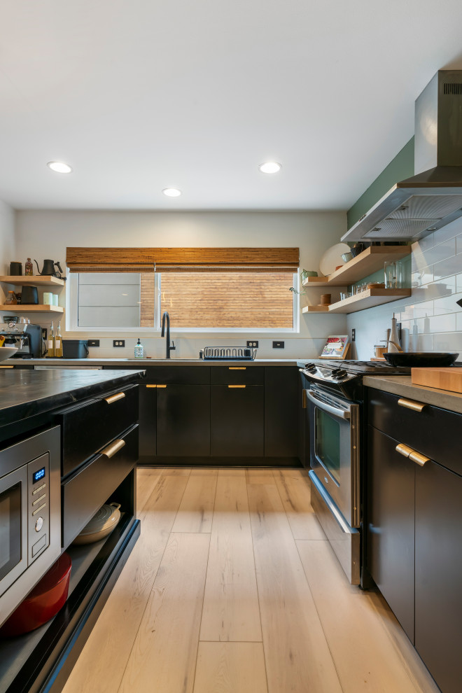 Photo of a large retro l-shaped kitchen/diner in Seattle with a built-in sink, flat-panel cabinets, black cabinets, marble worktops, white splashback, ceramic splashback, stainless steel appliances, vinyl flooring, an island, beige floors and grey worktops.
