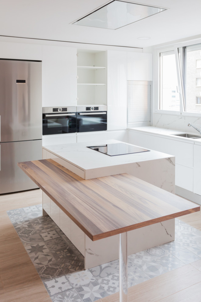 マドリードの大きいおしゃれなキッチン (ダブルシンク、白いキャビネット、白いキッチンパネル、シルバーの調理設備) の写真