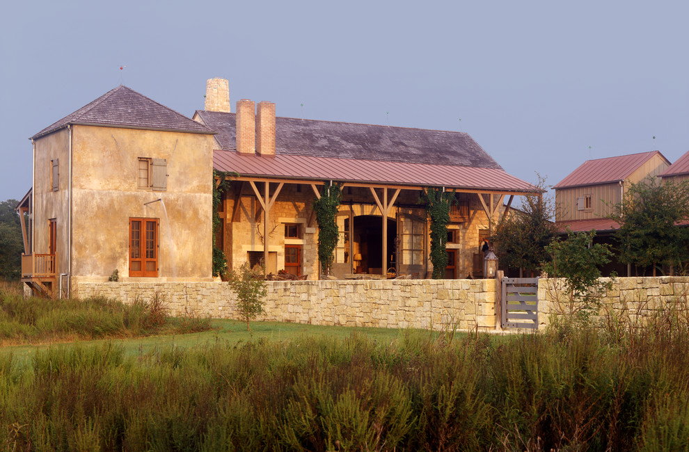 This is an example of an expansive country two-storey stucco beige exterior in Austin.