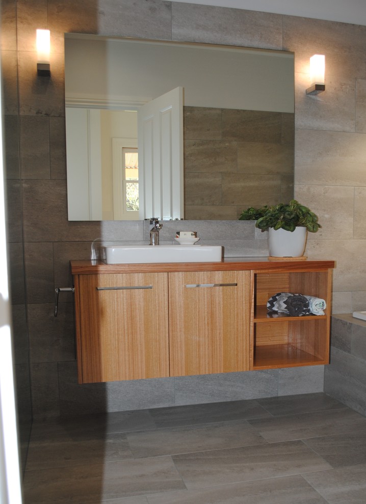 Design ideas for a mid-sized contemporary master bathroom in Other with furniture-like cabinets, light wood cabinets, a drop-in tub, an open shower, a two-piece toilet, gray tile, ceramic tile, grey walls, ceramic floors, a drop-in sink, wood benchtops, grey floor and an open shower.