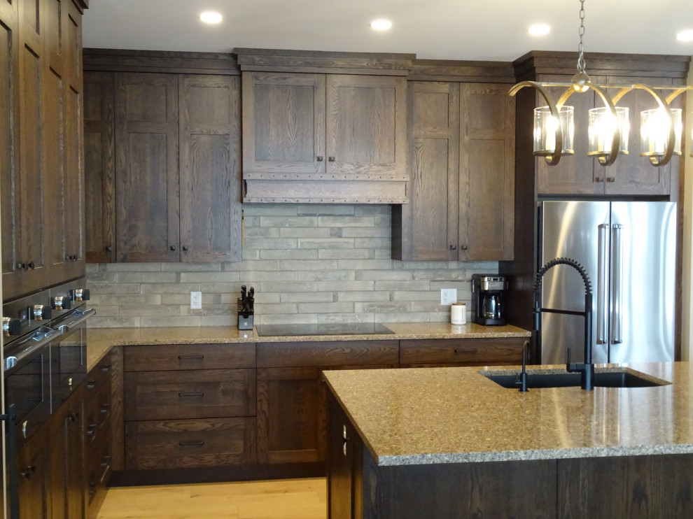 Inspiration for a large transitional l-shaped light wood floor and brown floor kitchen pantry remodel with an undermount sink, shaker cabinets, medium tone wood cabinets, granite countertops, gray backsplash, stone tile backsplash, stainless steel appliances, an island and multicolored countertops