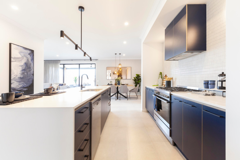 Photo of a single-wall open plan kitchen in Melbourne with an undermount sink, blue cabinets, quartz benchtops, white splashback, ceramic splashback, stainless steel appliances, ceramic floors, with island, beige floor and white benchtop.