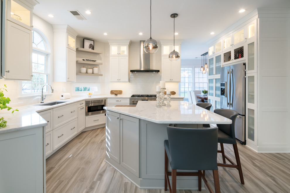 Inspiration for a large transitional l-shaped eat-in kitchen in Atlanta with an undermount sink, shaker cabinets, white cabinets, white splashback, subway tile splashback, stainless steel appliances, with island, brown floor, white benchtop, marble benchtops and porcelain floors.