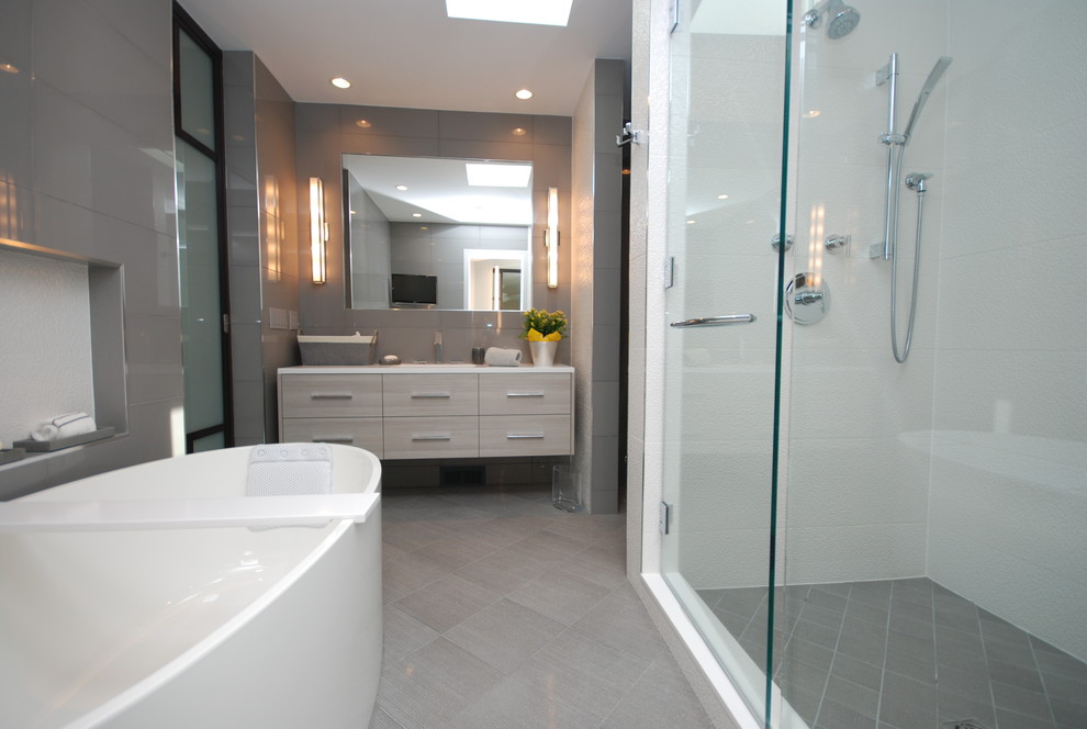 Design ideas for a mid-sized contemporary master bathroom in Chicago with flat-panel cabinets, grey cabinets, a freestanding tub, an alcove shower, gray tile, glass tile, grey walls, porcelain floors, an undermount sink, solid surface benchtops, grey floor and a hinged shower door.