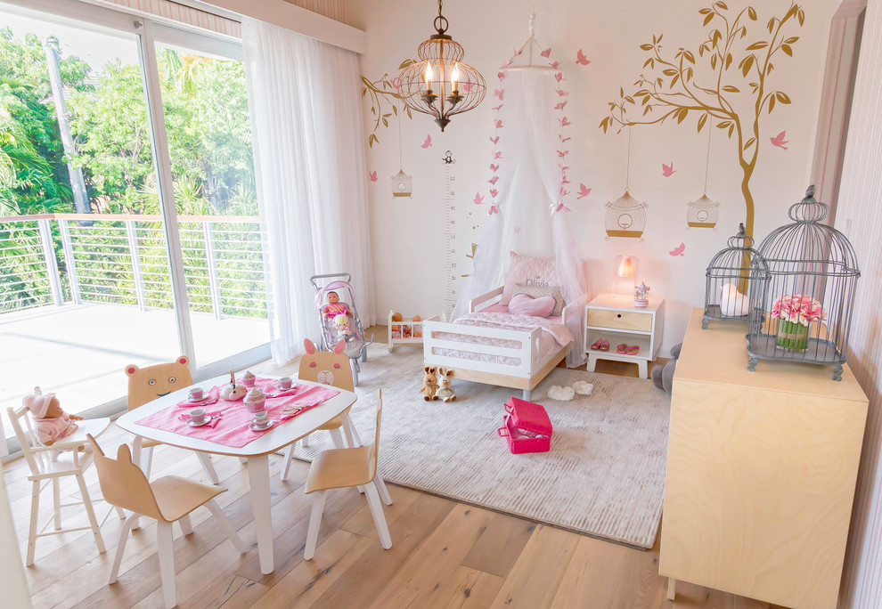 Photo of a large beach style nursery for girls in Miami with beige walls, light hardwood floors and beige floor.