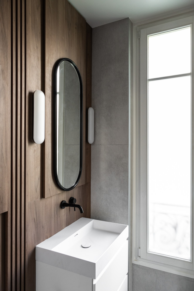 This is an example of a mid-sized contemporary 3/4 wet room bathroom in Paris with white cabinets, a wall-mount toilet, blue tile, brown walls, light hardwood floors, a vessel sink, white benchtops, a single vanity, a floating vanity, wood walls and a sliding shower screen.