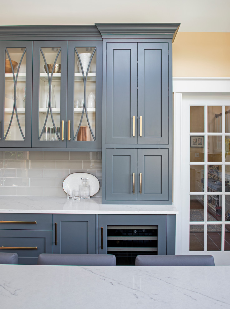 Kitchen - large transitional u-shaped medium tone wood floor kitchen idea with an undermount sink, gray cabinets, quartz countertops, gray backsplash, glass tile backsplash, stainless steel appliances, an island and white countertops