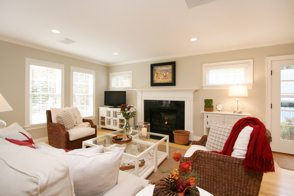 This is an example of a beach style open concept living room in Boston with light hardwood floors, a standard fireplace, a stone fireplace surround and a corner tv.