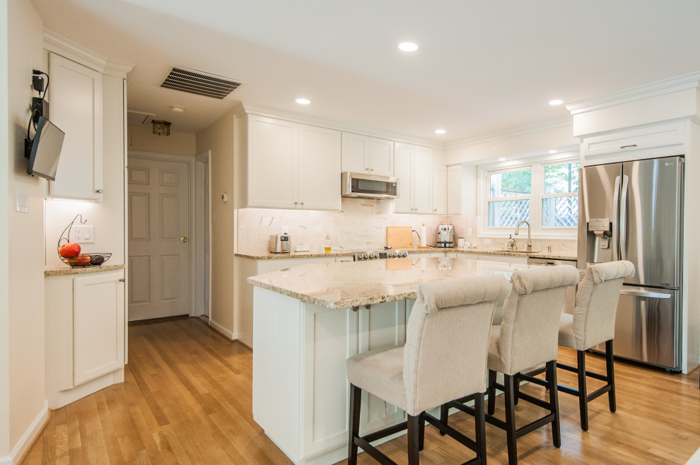 Kitchen - mid-sized transitional l-shaped medium tone wood floor and brown floor kitchen idea in DC Metro with shaker cabinets, white cabinets, granite countertops, beige backsplash, travertine backsplash, stainless steel appliances and an island