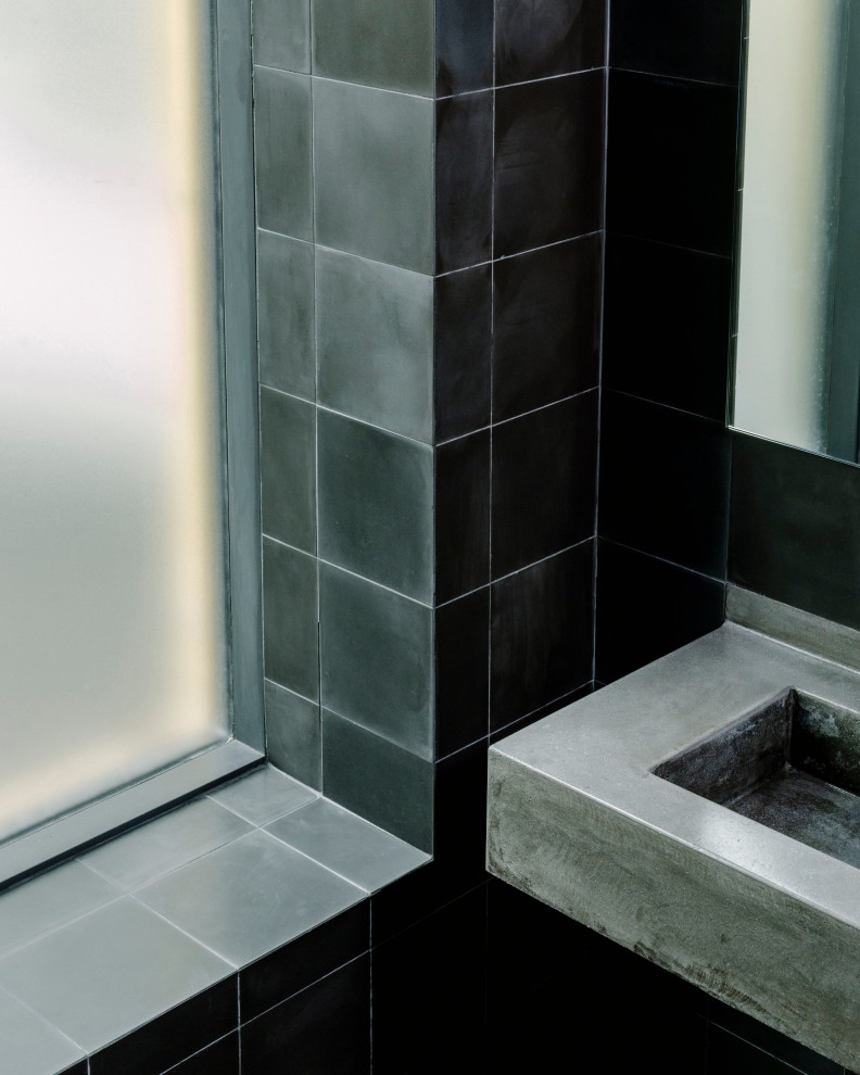ニューヨークにある高級な中くらいなコンテンポラリースタイルのおしゃれな浴室 (黒いタイル、セメントタイル、黒い壁、セメントタイルの床、コンクリートの洗面台、黒い床、黒い洗面カウンター、洗面台1つ) の写真