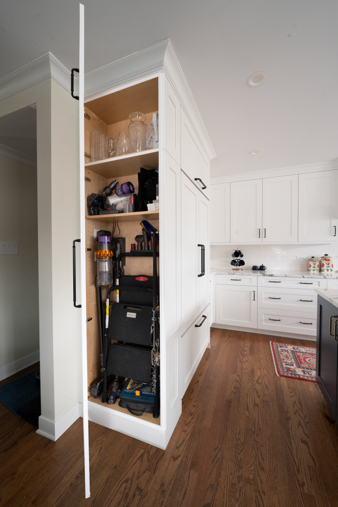 Example of a mid-sized transitional u-shaped medium tone wood floor and brown floor eat-in kitchen design in Chicago with an undermount sink, shaker cabinets, blue cabinets, quartz countertops, white backsplash, ceramic backsplash, stainless steel appliances, an island and white countertops
