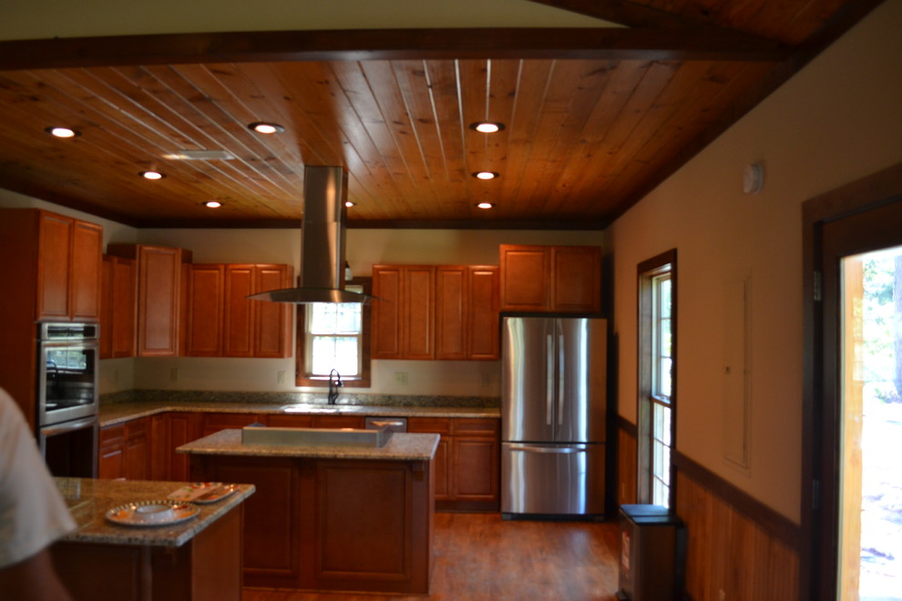 Mid-sized mountain style u-shaped medium tone wood floor kitchen photo in Atlanta with raised-panel cabinets, brown cabinets, granite countertops, stainless steel appliances and an island