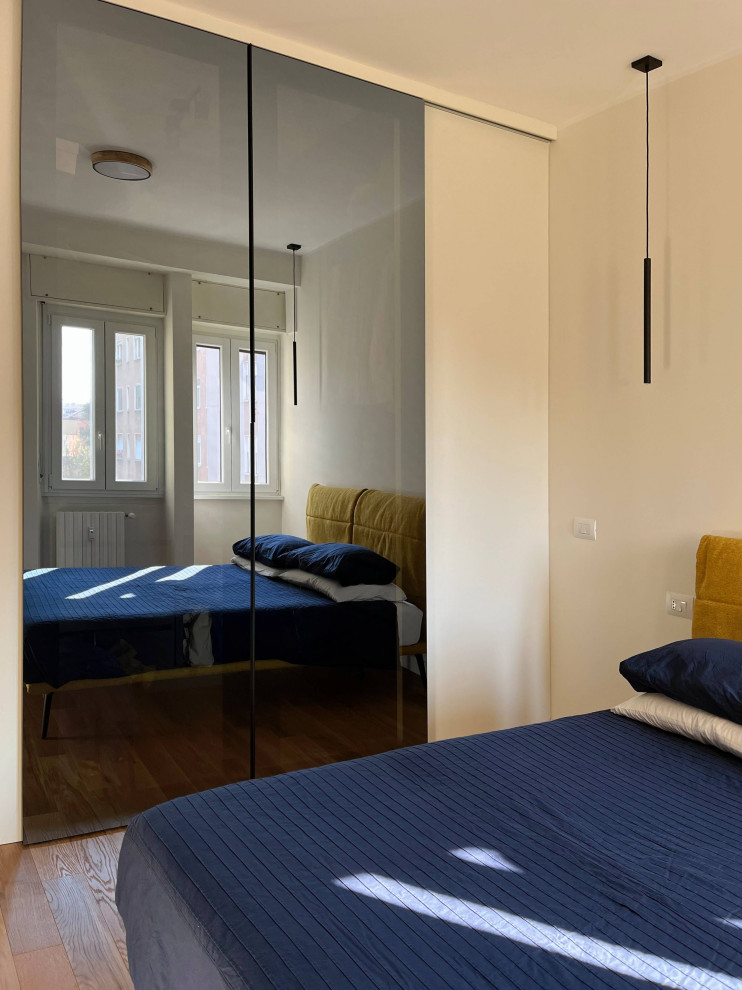 Modelo de dormitorio principal contemporáneo de tamaño medio con paredes beige y suelo de madera clara