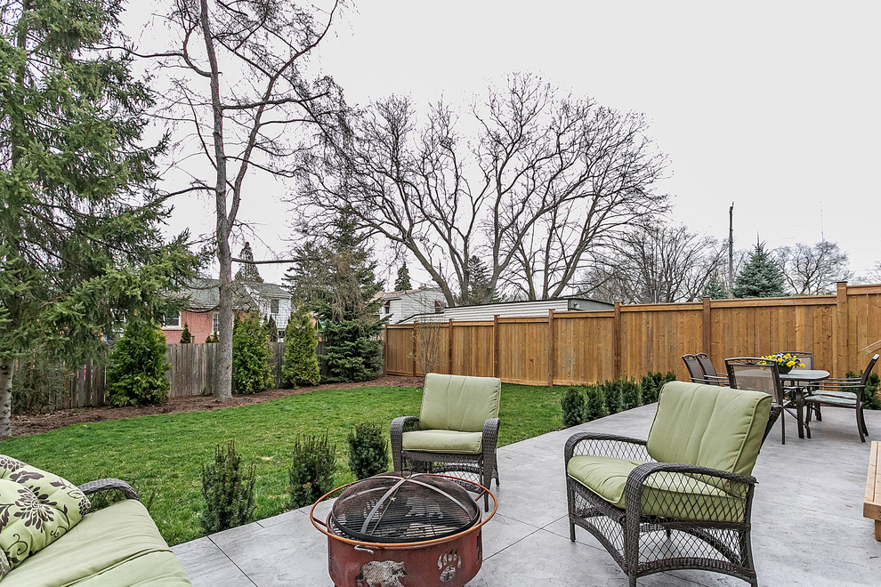 Inspiration for a mid-sized transitional backyard full sun garden in Toronto with a fire feature and natural stone pavers.