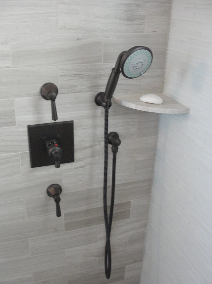 Photo of a mid-sized transitional 3/4 bathroom in New York with an alcove shower, gray tile, stone tile and grey walls.